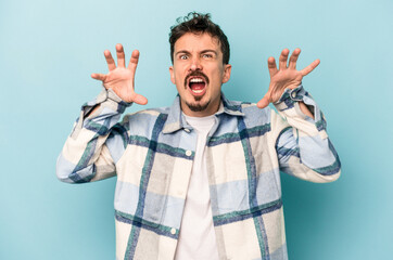Naklejka premium Young caucasian man isolated on blue background showing claws imitating a cat, aggressive gesture.