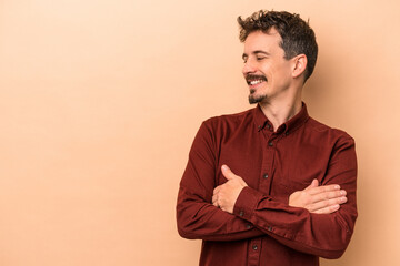 Fototapeta premium Young caucasian man isolated on beige background smiling confident with crossed arms.