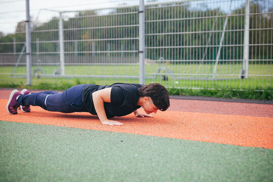 Young woman doing push-ups at outdoor gym
