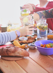 Top view of group of people having dinner together while sitting at wooden table. Food on the table. People eat fast food.