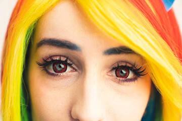 Rainbow-haired girl with red eyes and long dark lashes looking into the camera extreme close-up shot. High quality photo