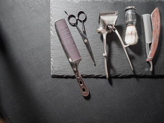vintage barber tools dangerous razor hairdressing scissors old manual clipper comb shaving brush. on a black slate surface. flat lay top view.