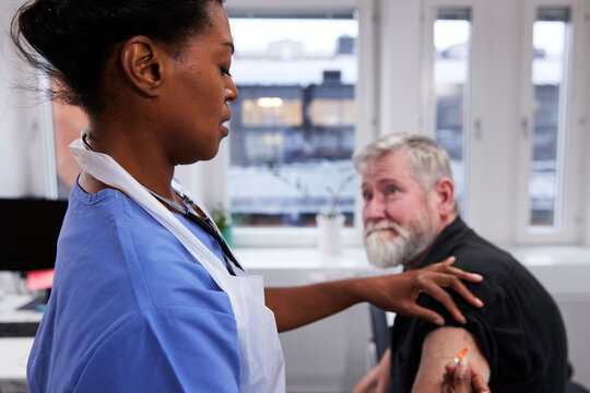 Female doctor vaccinating senior patient