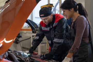 Side view portrait of two mechanics looking under hood inspecting car engine while working in auto repair shop, copy space