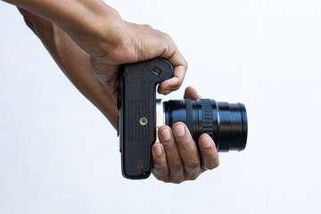 Isolated close-up of the hands and fingers of a Thai man holding an old black DSLR film camera.