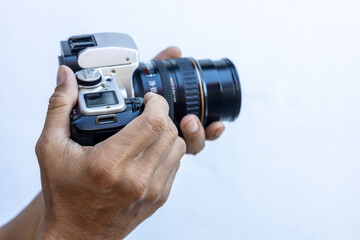 Isolated close-up of the hands and fingers of a Thai man holding an old black DSLR film camera.