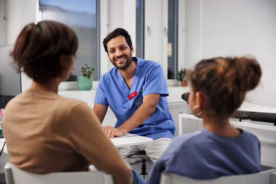 Male doctor talking to mother and daughter during appointment