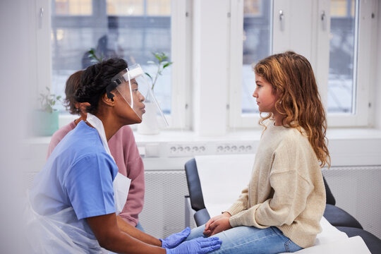 Female doctor talking to girl patient during appointment
