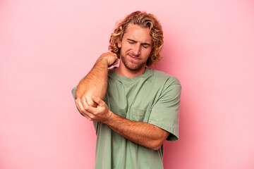 Young caucasian man isolated on pink background massaging elbow, suffering after a bad movement.
