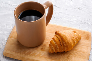 coffee mug and croissant on cutting board
