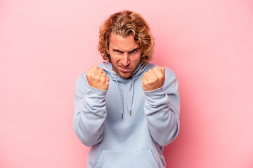 Young caucasian man isolated on pink background upset screaming with tense hands.