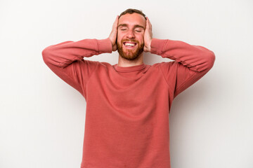 Young caucasian man isolated on white background laughs joyfully keeping hands on head. Happiness concept.