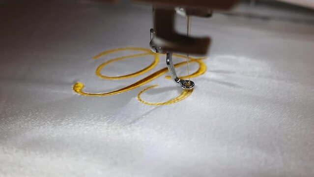 Machine embroider the inscription "B" on a white satin robe.
Inscription bride with golden thread. Wedding day preparation. Elegant bridal lingerie. Close up. Full Hd 50 fps Video.