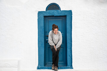 Fototapeta na wymiar chica riendo frente a una puerta azul