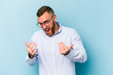 Young caucasian man isolated on blue background pointing with finger at you as if inviting come closer.