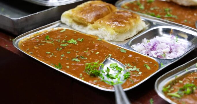 Closeup Zooming In shot of Famous Indian Fast Food Dish called Pav Bhaji, a curry made by mashing mixed vegetables in spices, masalas and served with roasted bread called as pav, Mumbai, India. 4805.