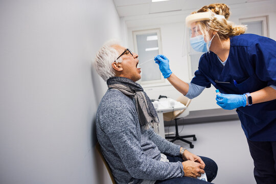 Female doctor performing covid-19 swab test on senior man