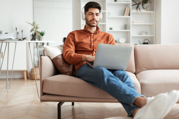 Fototapeta premium Focused Arab man in headphones using pc at home