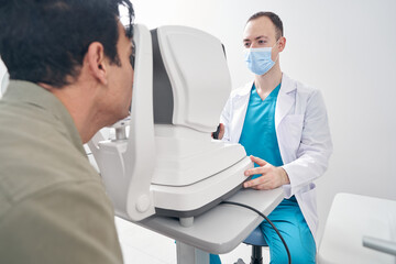 Obraz premium Male doctor working at the refraction machine