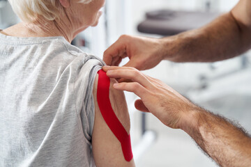 Medical worker easing arm pain with elastic therapeutic tape