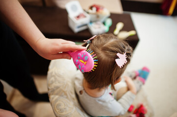 Fototapeta premium Mother and daughter weekend together at home, mom making hairstyle for baby girl.
