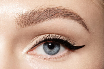 Female blue eye with trendy perfect fashion makeup, eyeliner on eyelid, ideal shaped eyebrow,...