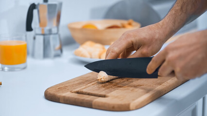 partial view of man cutting banana on chopping board in kitchen