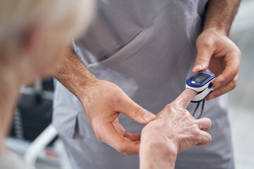 Doctor applying pulse oximeter to patient finger