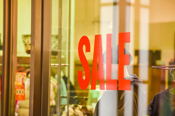 A Sale sign on glass wall outside a clothing store or apparel shop 