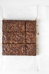 Flat lay of brownies, brownies that have been cut into squares, caramel brownies on white parchment paper