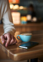 Close up of man's hand with latte art coffee cup in cafe, selective focus, food and drink concept