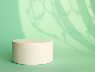 Abstract empty white podium for the presentation of packaging and cosmetics, shadow on the wall. Minimalism