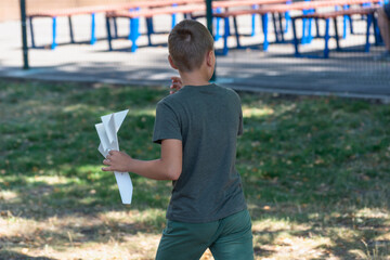 Boy (child) with a paper plane in the park.