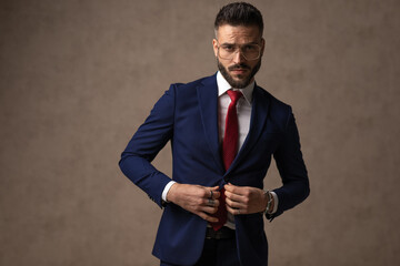 young sexy businessman arranging his suit, wearing eyeglasses