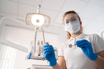 Fototapeta na wymiar Dentist woman alone holding dental instruments, looking at the camera. Personal or patient point of view, POV. dental treatment concept.