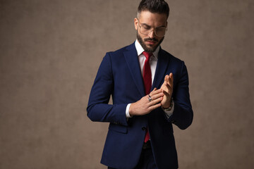 businessman rubbing his palms, looking down, wearing eyeglasses