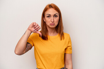 Young caucasian woman isolated on white background showing a dislike gesture, thumbs down....