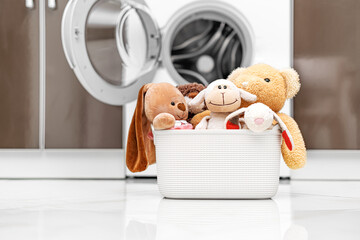 Children's toys in a laundry basket on the background of a washing machine.