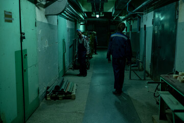 Fototapeta na wymiar Wide angle view at zombies walking in dark industrial hallway lit by creepy green light, copy space