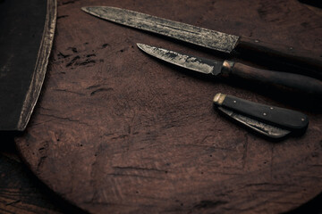 old rusty knives near a penknife and cleaver blade on rustic table top
