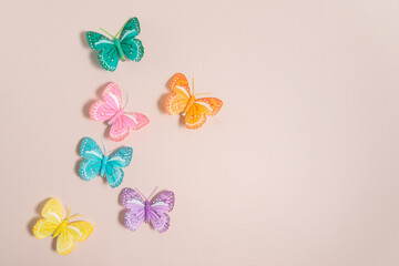 multicolored handmade butterflies on a pale pink background, free space for text, elegant spring composition