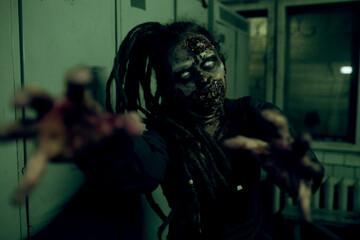 Waist up shot of gory female zombie reaching out to camera in dark setting lut by green light