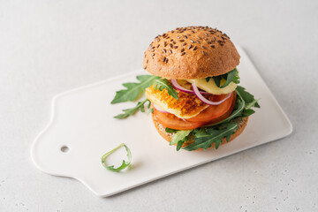 Halloumi burger with tomato, arugula and red onion. Sandwich with halloumi cheese and vegetables, mediterranean cuisine