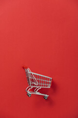 close-up photo of shopping trolley on red background. minimalistic photo of pushcart