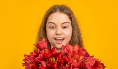 Naklejka premium surprised child hold spring tulip flowers on yellow background