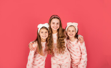 Homewear and pyjamas for girls. Happy sisters in homewear pink background