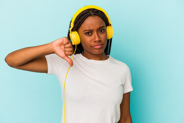 Young African American woman listening to music isolated on blue background  showing a dislike gesture, thumbs down. Disagreement concept.