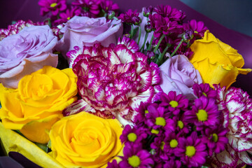 Close-up bouquet of yellow and purple roses, pink carnations and chrysanthemums. An image for a flower shop, a postcard. Selective focus.