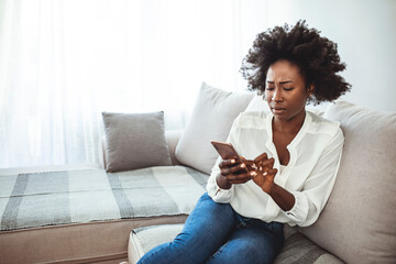 Angry young African woman looking at smartphone, frustrated with no signal or message of deception, crazy woman disappointed reading bad news on phone, upset girl gets negative answer or rejected 