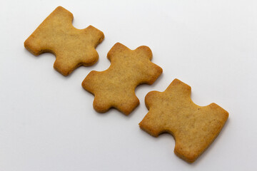 closeup of the jigsaw, puzzle shaped cookies white background, horizontal copy space pastry background. Team building, banner